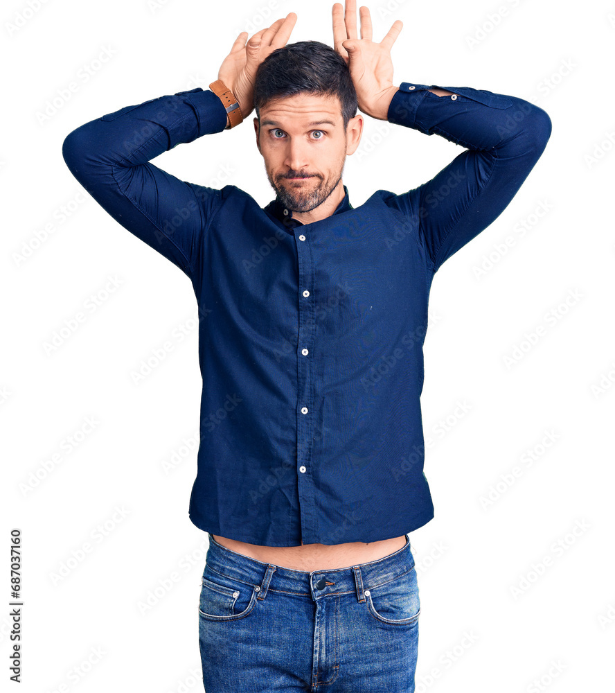 Young handsome man wearing casual shirt doing bunny ears gesture with hands palms looking cynical and skeptical. easter rabbit concept. Young handsome man wearing casual shirt doing bunny ears gesture with hands palms looking cynical and skeptical. easter rabbit concept.