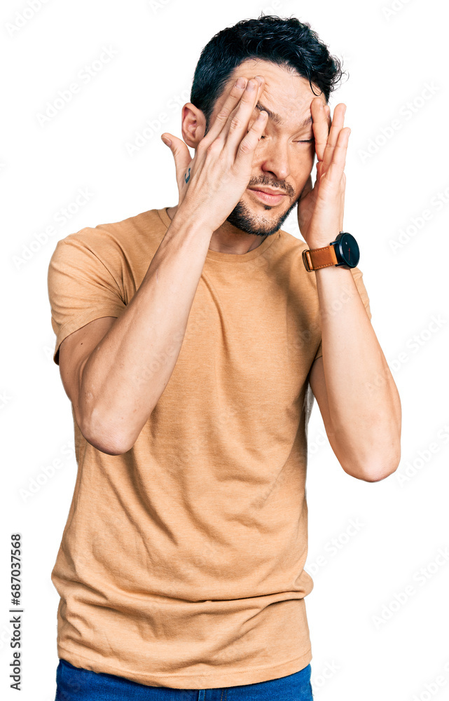 Hispanic man with beard wearing casual t shirt with hand on head, headache because stress. suffering migraine. Hispanic man with beard wearing casual t shirt with hand on head, headache because stress. suffering migraine.