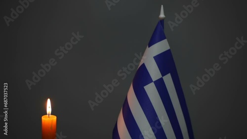  Burning wax candle and Greek flag on a gray background. Free space for text. photo