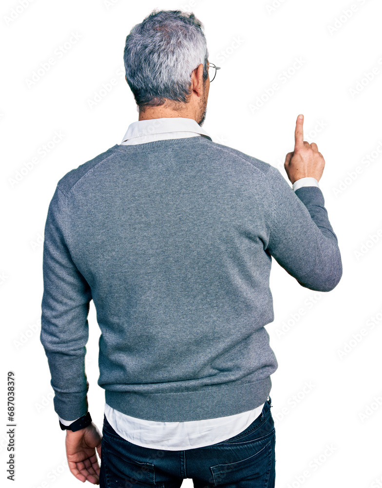 Middle age hispanic with grey hair wearing glasses posing backwards pointing ahead with finger hand Middle age hispanic with grey hair wearing glasses posing backwards pointing ahead with finger hand