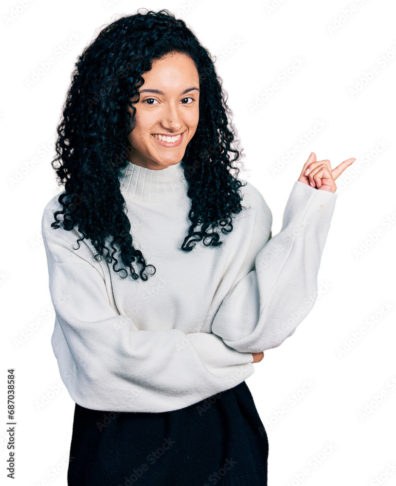 Young hispanic woman with curly hair wearing casual sweater with a big smile on face, pointing with hand and finger to the side looking at the camera. Young hispanic woman with curly hair wearing casual sweater with a big smile on face, pointing with hand and finger to the side looking at the camera.