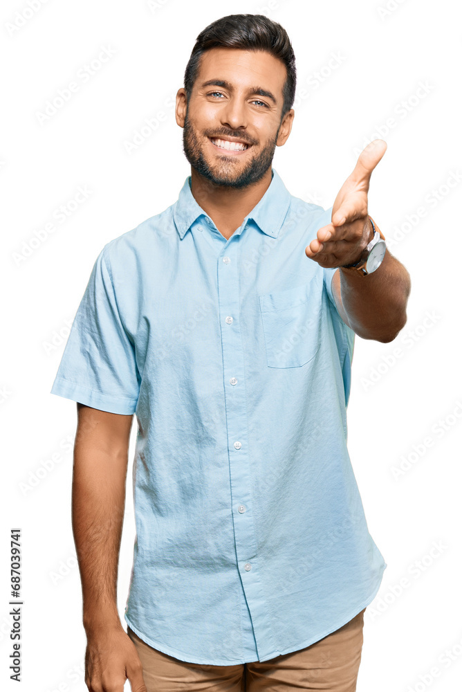 Handsome hispanic man wearing casual clothes smiling friendly offering handshake as greeting and welcoming. successful business. Handsome hispanic man wearing casual clothes smiling friendly offering handshake as greeting and welcoming. successful business.