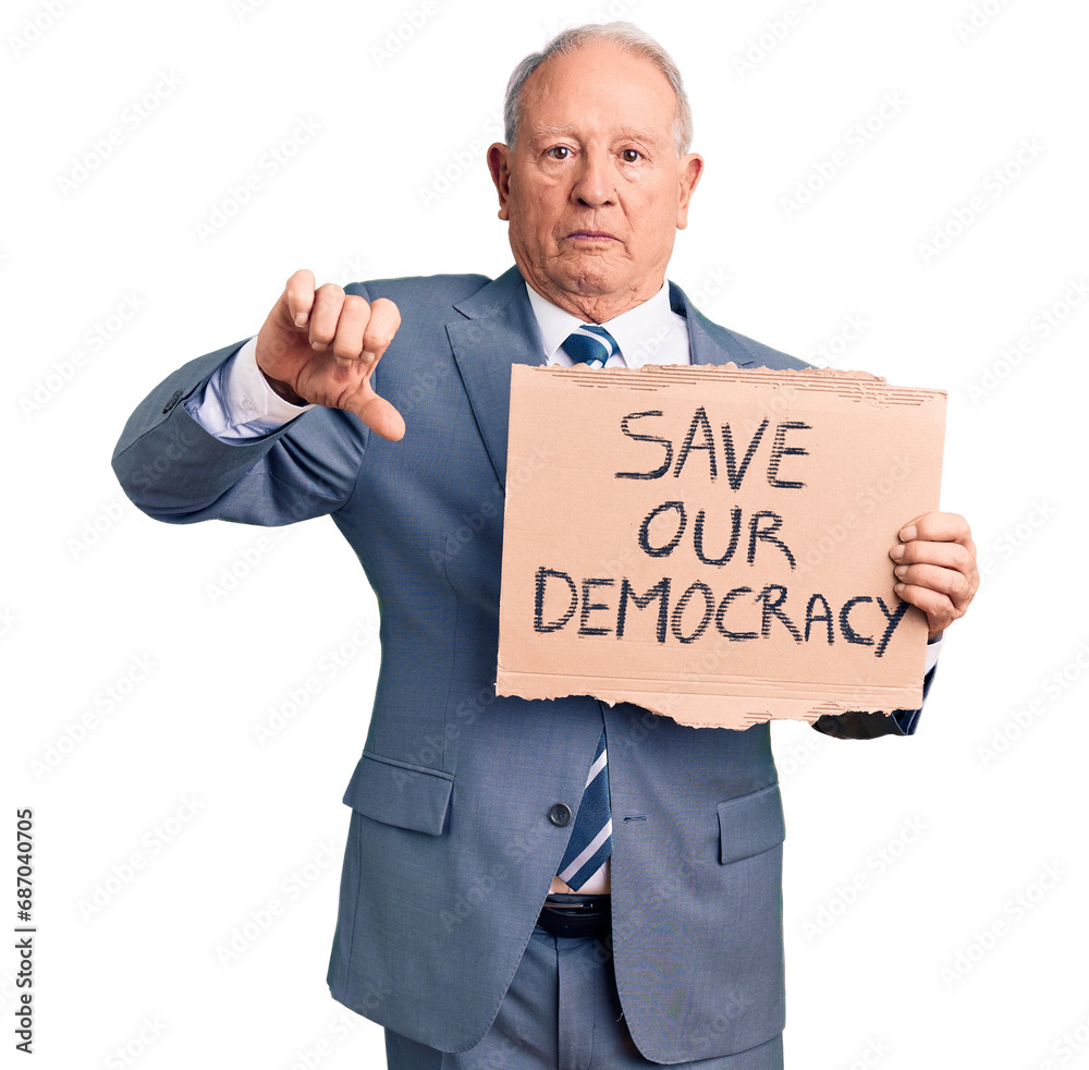 Senior handsome grey-haired man holding save our democracy cardboard banner with angry face, negative sign showing dislike with thumbs down, rejection concept Senior handsome grey-haired man holding save our democracy cardboard banner with angry face, negative sign showing dislike with thumbs down, rejection concept