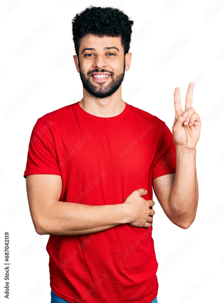 Young arab man with beard wearing casual red t shirt smiling with happy face winking at the camera doing victory sign. number two. Young arab man with beard wearing casual red t shirt smiling with happy face winking at the camera doing victory sign. number two.