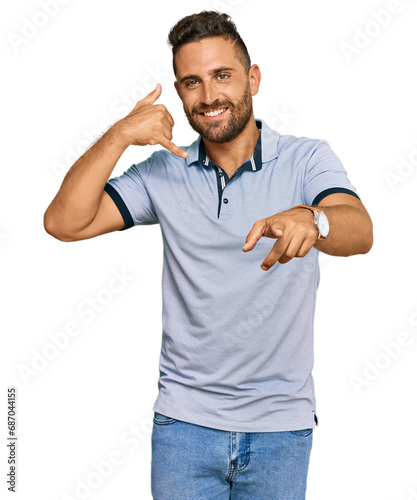 Handsome man with beard wearing casual clothes smiling doing talking on the telephone gesture and pointing to you. call me.