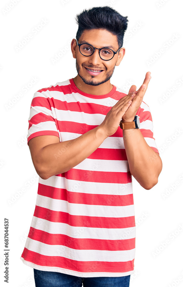 Naklejka premium Handsome latin american young man wearing casual clothes and glasses clapping and applauding happy and joyful, smiling proud hands together