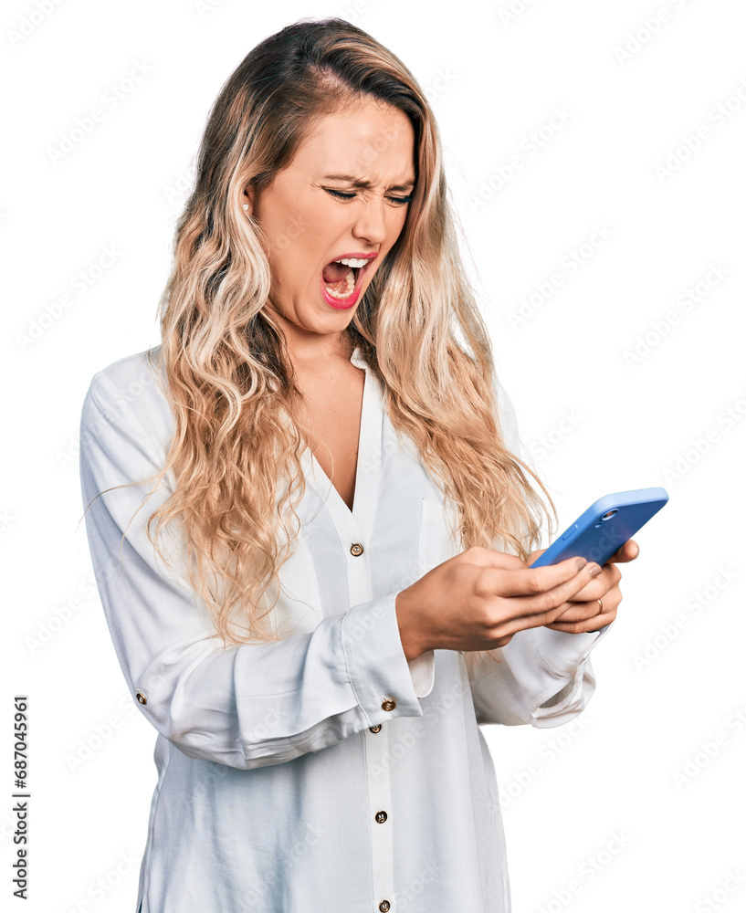 Young blonde woman using smartphone angry and mad screaming frustrated and furious, shouting with anger. rage and aggressive concept. Young blonde woman using smartphone angry and mad screaming frustrated and furious, shouting with anger. rage and aggressive concept.
