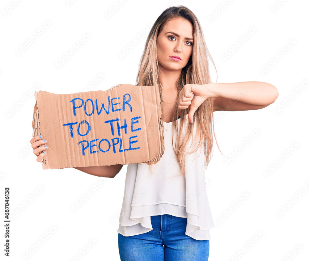 Young beautiful blonde woman holding power to the people cardboard banner with angry face, negative sign showing dislike with thumbs down, rejection concept