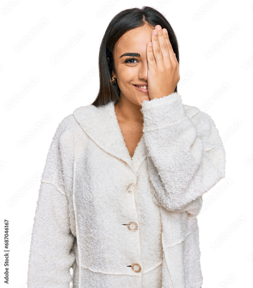 Young brunette woman wearing casual clothes covering one eye with hand, confident smile on face and surprise emotion. Young brunette woman wearing casual clothes covering one eye with hand, confident smile on face and surprise emotion.
