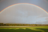 Large bright weather rainbow over agricultural field