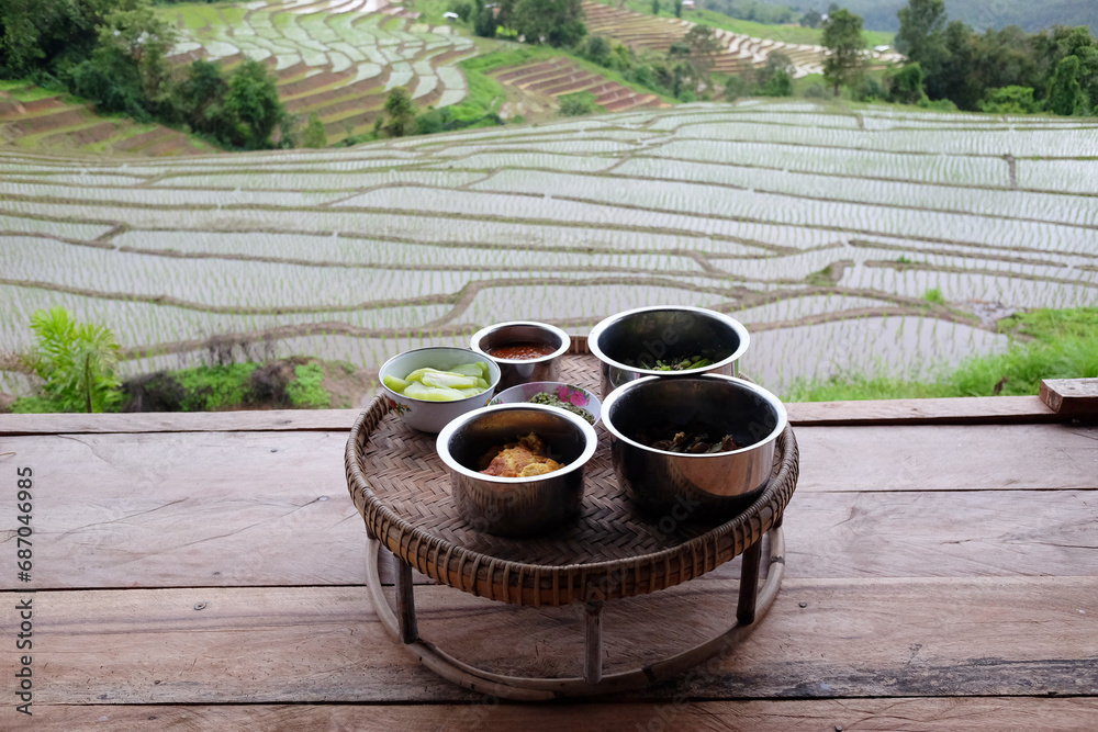 Kantoke, Kind of wooden utensil in northern of Thailand for put the foods to serve on terrace of homestay and Paddy rice fields on mountain in rainy season in countryside. Food and travel concept Kantoke, Kind of wooden utensil in northern of Thailand for put the foods to serve on terrace of homestay and Paddy rice fields on mountain in rainy season in countryside. Food and travel concept