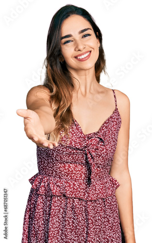 Beautiful hispanic woman wearing summer dress smiling friendly offering handshake as greeting and welcoming. successful business. © Krakenimages.com