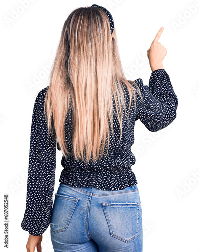 Young beautiful blonde woman wearing casual clothes posing backwards pointing ahead with finger hand photo