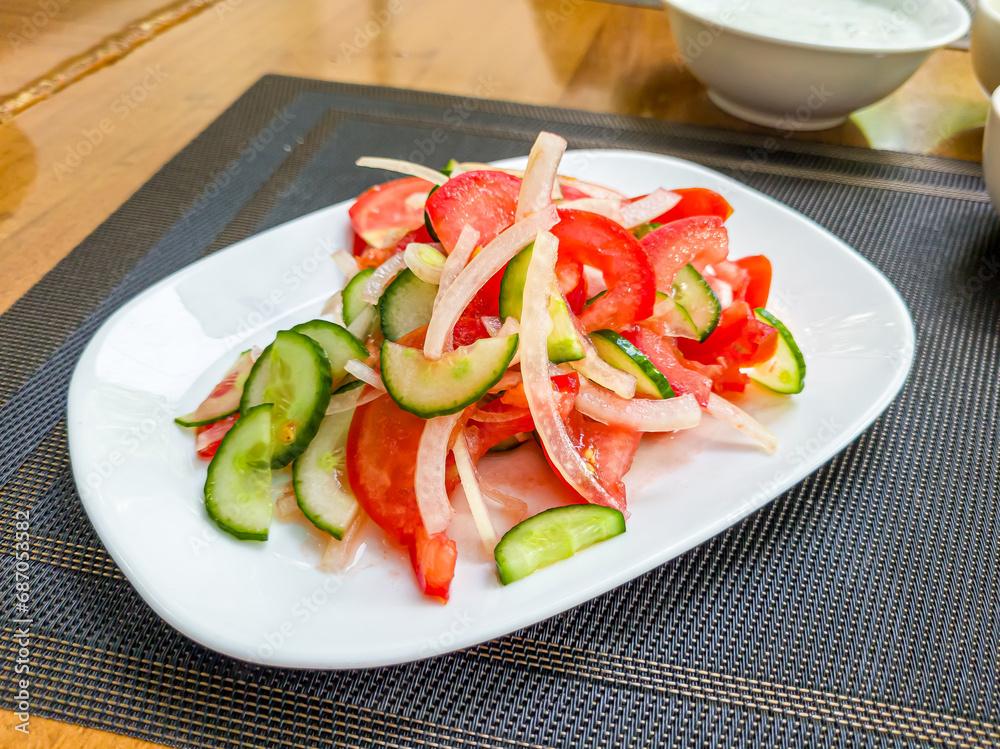 A very simple salad of tomatoes, cucumbers and onions on a white plate