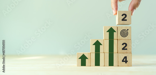 Business growth concept in 2024. Business goals and achievement. Sustainable development. Wooden cubes inscripted 2024 and growth icons on smart background. Positive indicators and trend concept. photo
