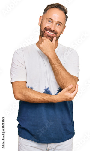 Handsome middle age man wearing casual tie dye tshirt looking confident at the camera smiling with crossed arms and hand raised on chin. thinking positive.