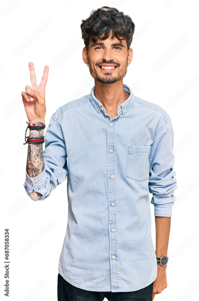 Young hispanic man wearing casual clothes smiling looking to the camera showing fingers doing victory sign. number two. Young hispanic man wearing casual clothes smiling looking to the camera showing fingers doing victory sign. number two.