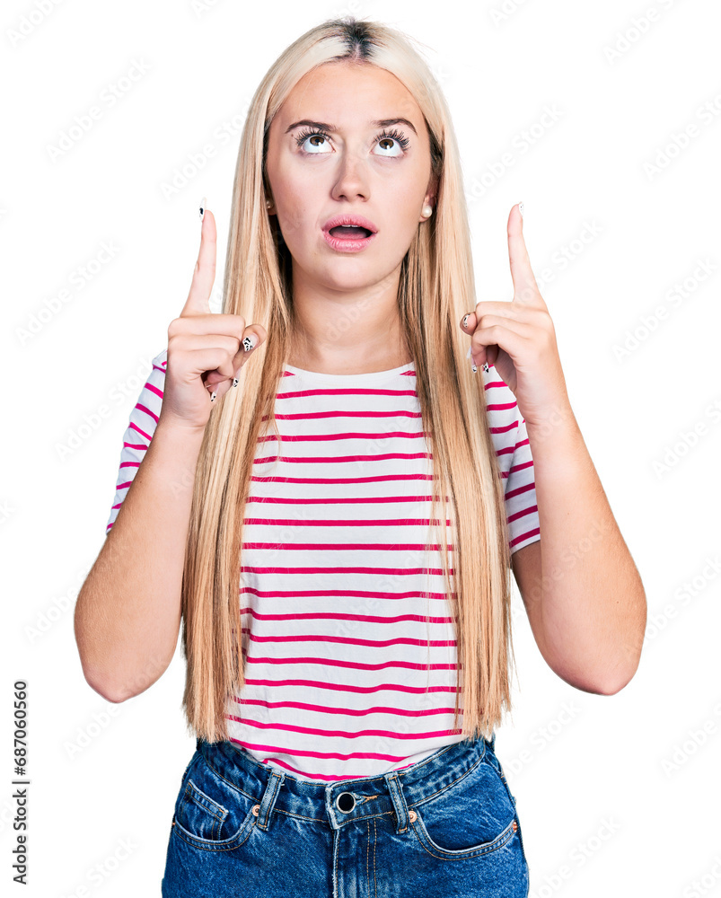 Φωτογραφία Beautiful blonde woman wearing casual striped t shirt amazed and surprised looking up and pointing with fingers and raised arms