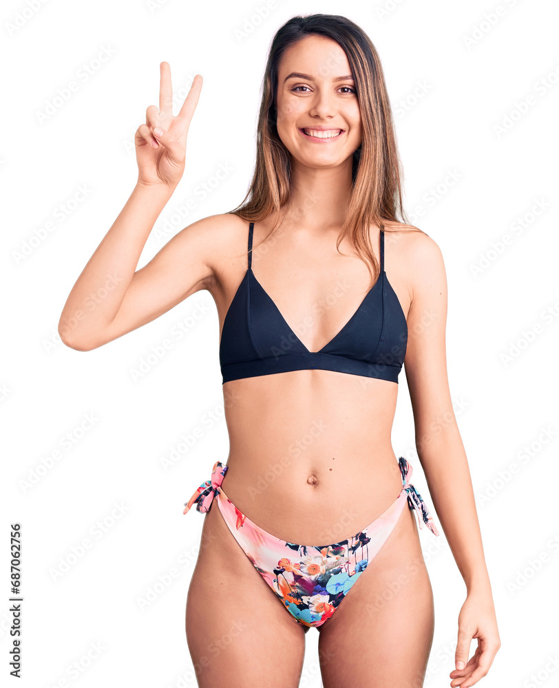 Young beautiful girl wearing bikini smiling with happy face winking at the camera doing victory sign. number two. Young beautiful girl wearing bikini smiling with happy face winking at the camera doing victory sign. number two.