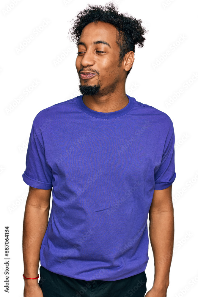 Young african american man with beard wearing casual purple t shirt smiling looking to the side and staring away thinking. Young african american man with beard wearing casual purple t shirt smiling looking to the side and staring away thinking.