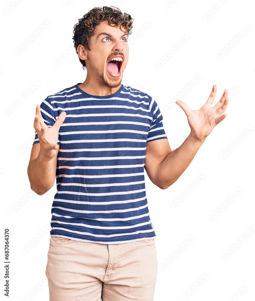 Naklejka premium Young handsome man with curly hair wearing casual clothes crazy and mad shouting and yelling with aggressive expression and arms raised. frustration concept.