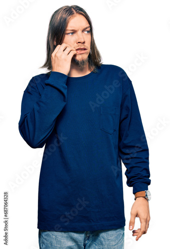 Handsome caucasian man with long hair wearing casual winter sweater looking stressed and nervous with hands on mouth biting nails. anxiety problem.