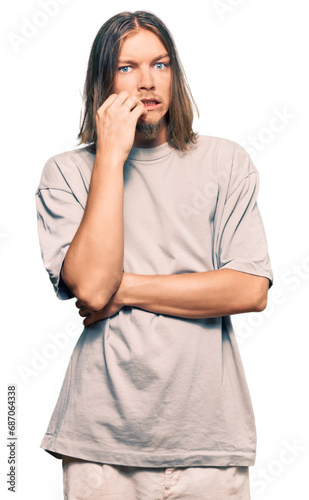 Handsome caucasian man with long hair wearing casual clothes looking stressed and nervous with hands on mouth biting nails. anxiety problem.