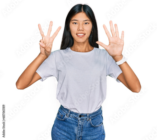 Beautiful young asian woman wearing casual white t shirt showing and pointing up with fingers number eight while smiling confident and happy.