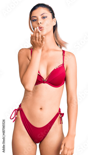 Young beautiful woman wearing bikini looking at the camera blowing a kiss with hand on air being lovely and sexy. love expression. © Krakenimages.com