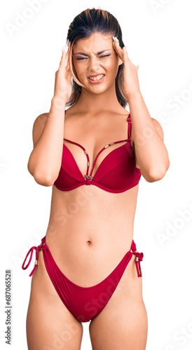 Young beautiful woman wearing bikini with hand on head, headache because stress. suffering migraine. © Krakenimages.com