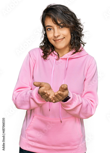 Young hispanic woman wearing casual sweatshirt smiling with hands palms together receiving or giving gesture. hold and protection