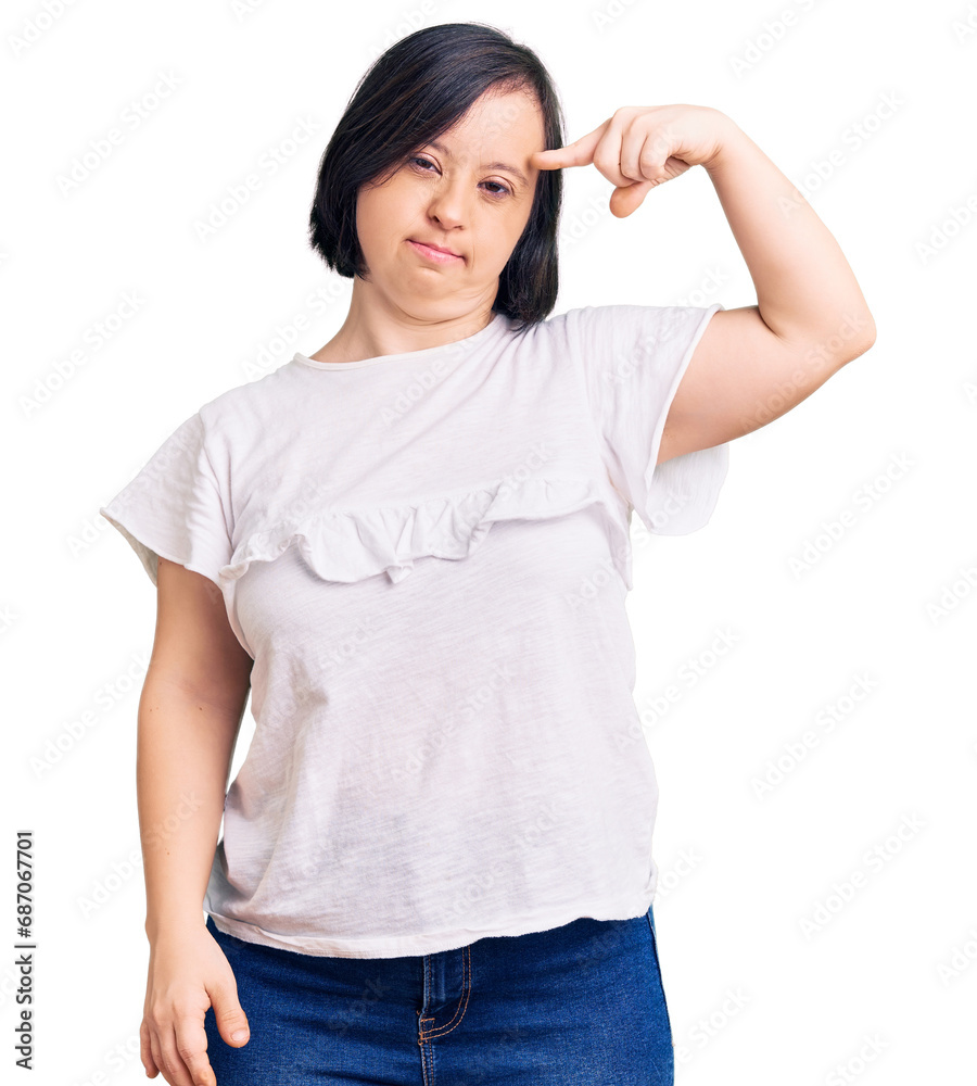 Brunette woman with down syndrome wearing casual white tshirt pointing unhappy to pimple on forehead, ugly infection of blackhead. acne and skin problem Brunette woman with down syndrome wearing casual white tshirt pointing unhappy to pimple on forehead, ugly infection of blackhead. acne and skin problem