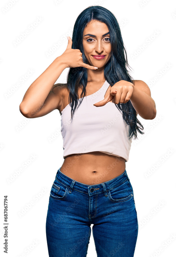 Beautiful hispanic woman wearing casual clothes smiling doing talking on the telephone gesture and pointing to you. call me. Beautiful hispanic woman wearing casual clothes smiling doing talking on the telephone gesture and pointing to you. call me.
