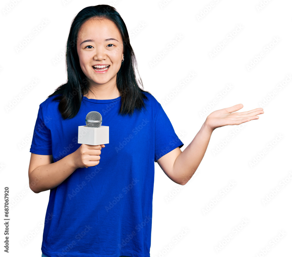 Young chinese woman holding reporter microphone celebrating achievement with happy smile and winner expression with raised hand Young chinese woman holding reporter microphone celebrating achievement with happy smile and winner expression with raised hand