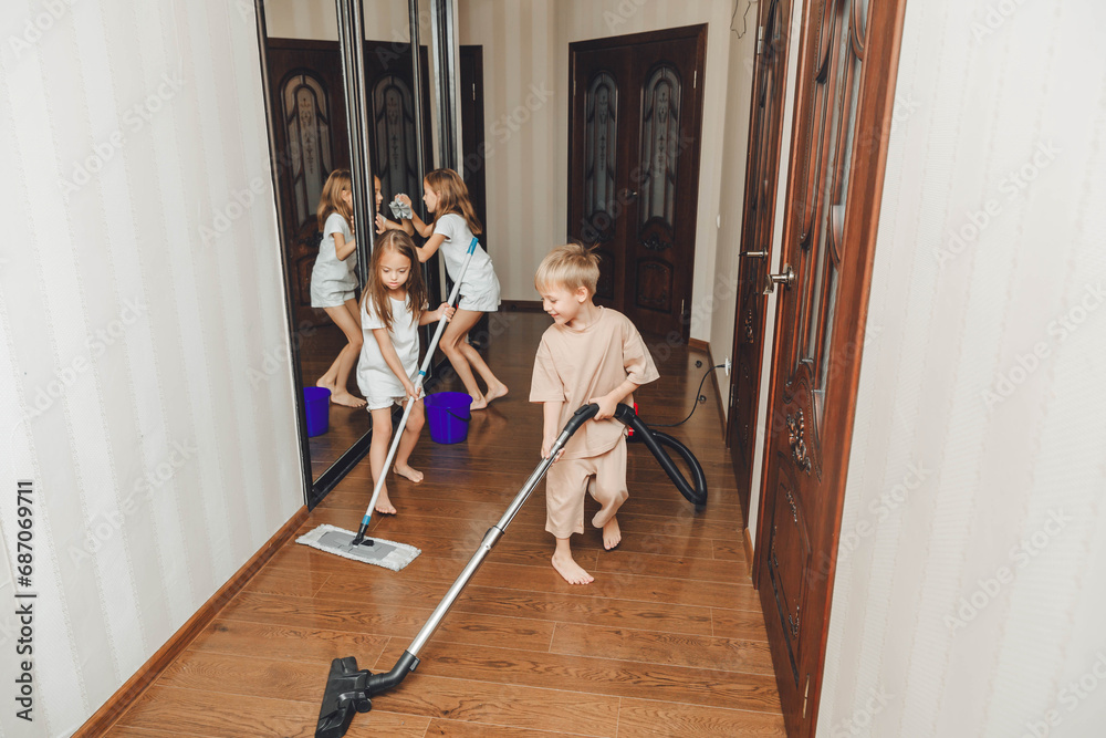 The concept of cleaning an apartment on the weekend. Mom and her children are cleaning the house, Woman and little children are sweeping, vacuuming the floor, dancing
