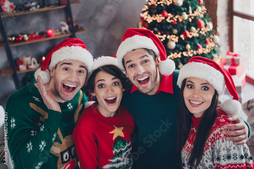 Photo of group positive impressed group mates cuddle open mouth new year surprise tree garland apartment indoors
