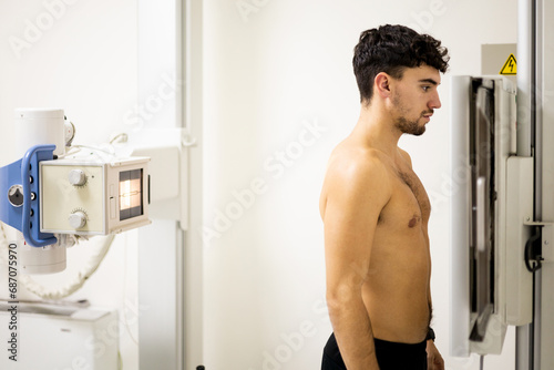 A young Caucasian man undergoes an x-ray machine for a back X-ray inside a hospital to check for injuries or diseases affecting the discs or joints of the spine. X-ray concept. photo