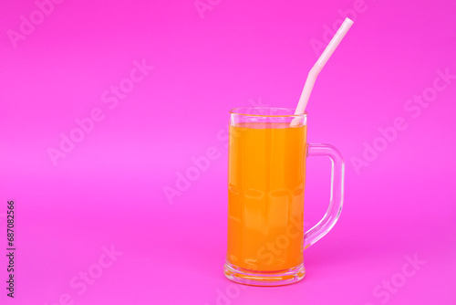 Glass mug of orange juice with drinking straw. Pink background. Concept, morning refreshing beverage. Sweet, testy and high vitamin C. 