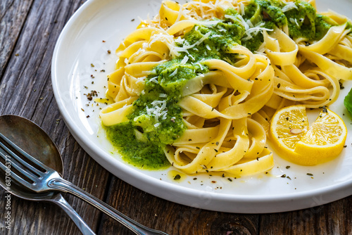 Tagliatelle with basil pesto sauce on wooden table