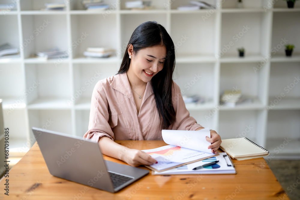 Asian businesswoman sitting and working check documents analyze market reports. Review and compare report data. Asian businesswoman sitting and working check documents analyze market reports. Review and compare report data.