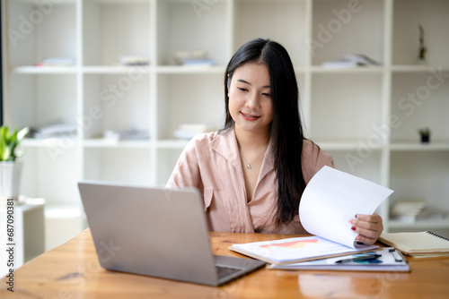 Asian businesswoman sitting and working check documents analyze market reports. Review and compare report data.