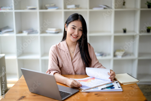 Asian businesswoman sitting and working check documents analyze market reports. Review and compare report data. © Wasana