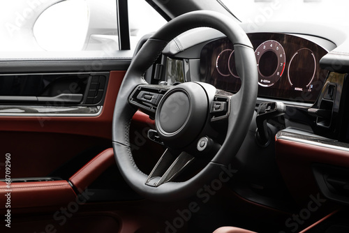 Interior of new modern SUV car with steering wheel, shift lever and dashboard, climate control, speedometer, display.  Red leather interior