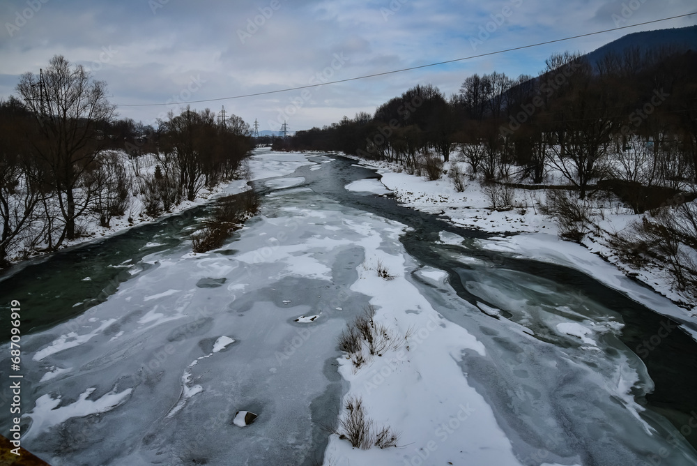 Fototapeta premium Mountain village in the Ukrainian Carpathians next to the river, winter landscape