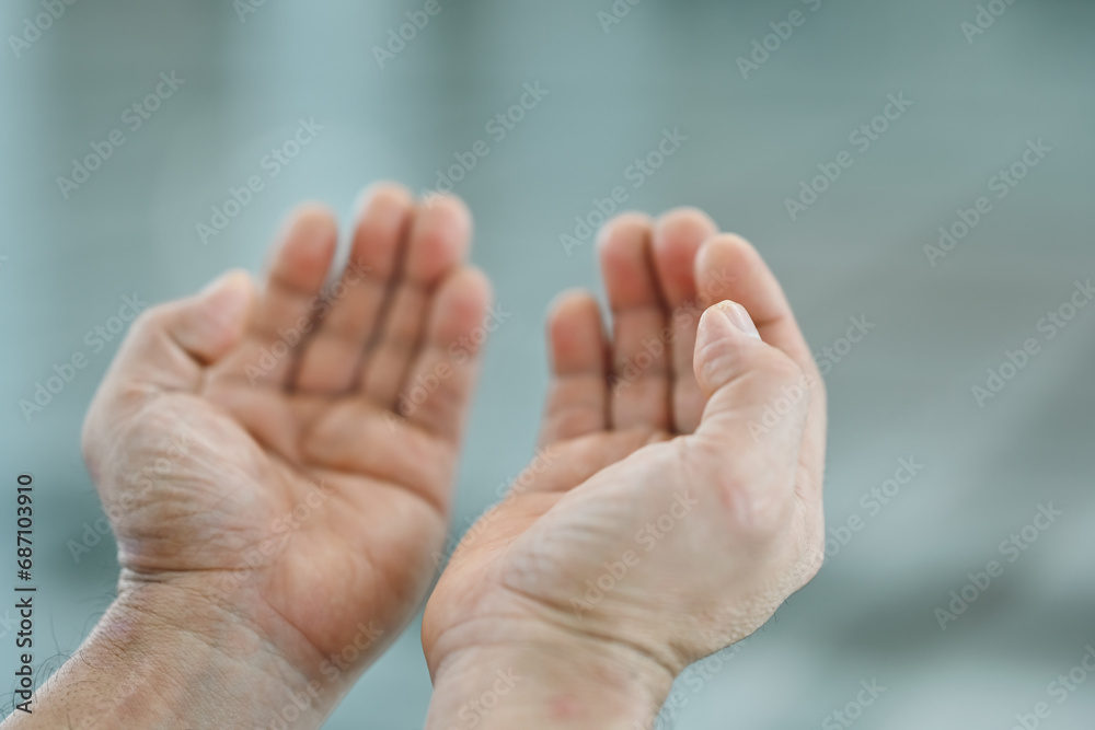 Close-up of a Muslim man praying with hands up in the air in the mosque, Religion praying concept