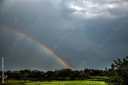 Double rainbow in the sky during rain in a cloudy sky over a village 