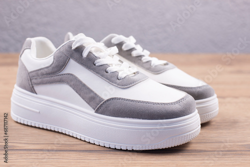 White sports sneakers on a wooden background. Footwear