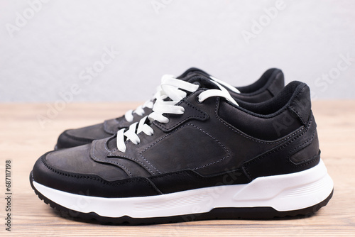 Black sneakers on a wooden background. Sports shoes.