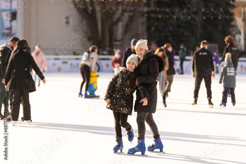 Action shot of beautiful woman teaching her daughter how to ice skate © Angelov