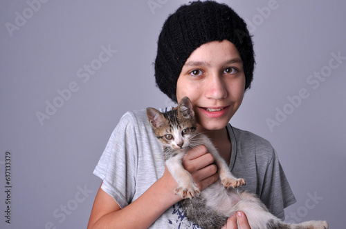 Menino com gatinho doméstico fofo em retrato de estúdio, adoção de animais conciente , amor aos animais  photo